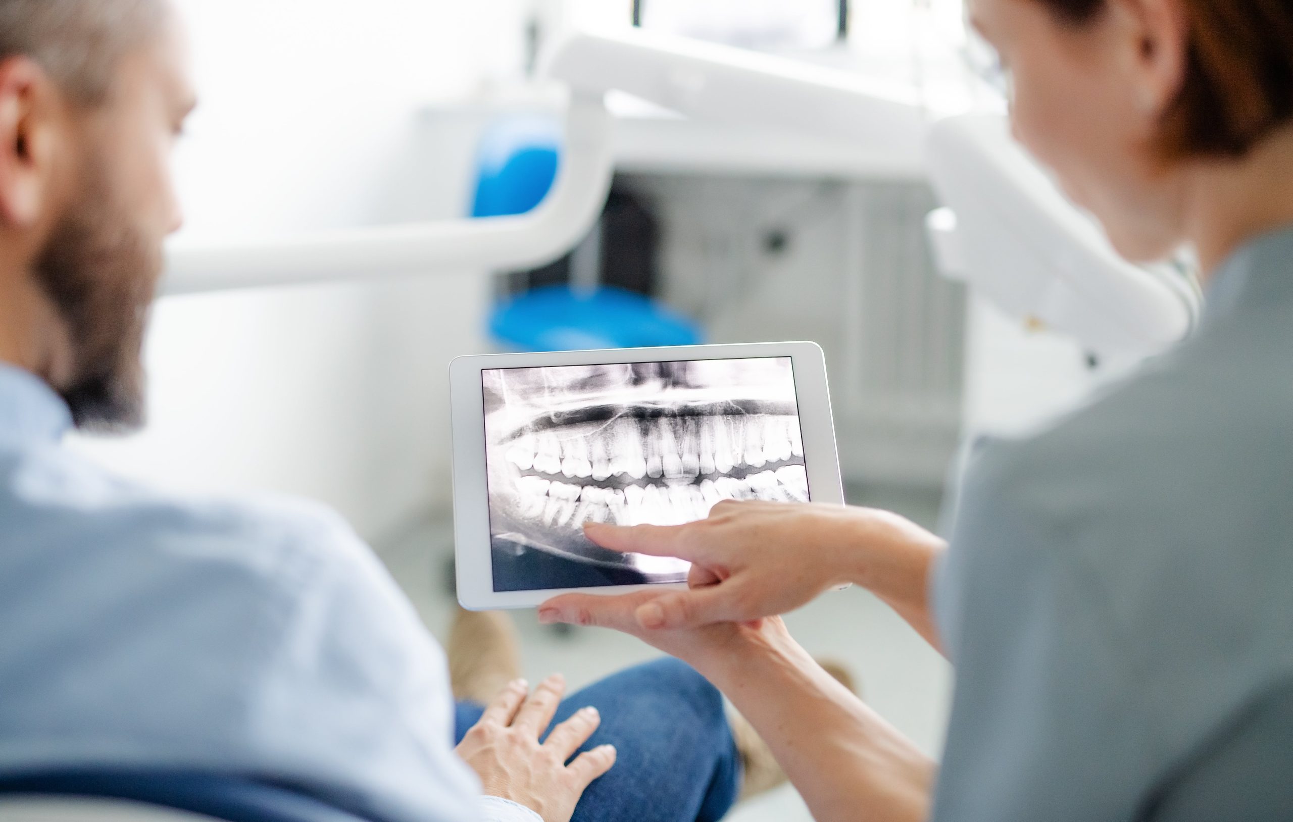 Dentist and man looking at scan of teeth in oral surgery room